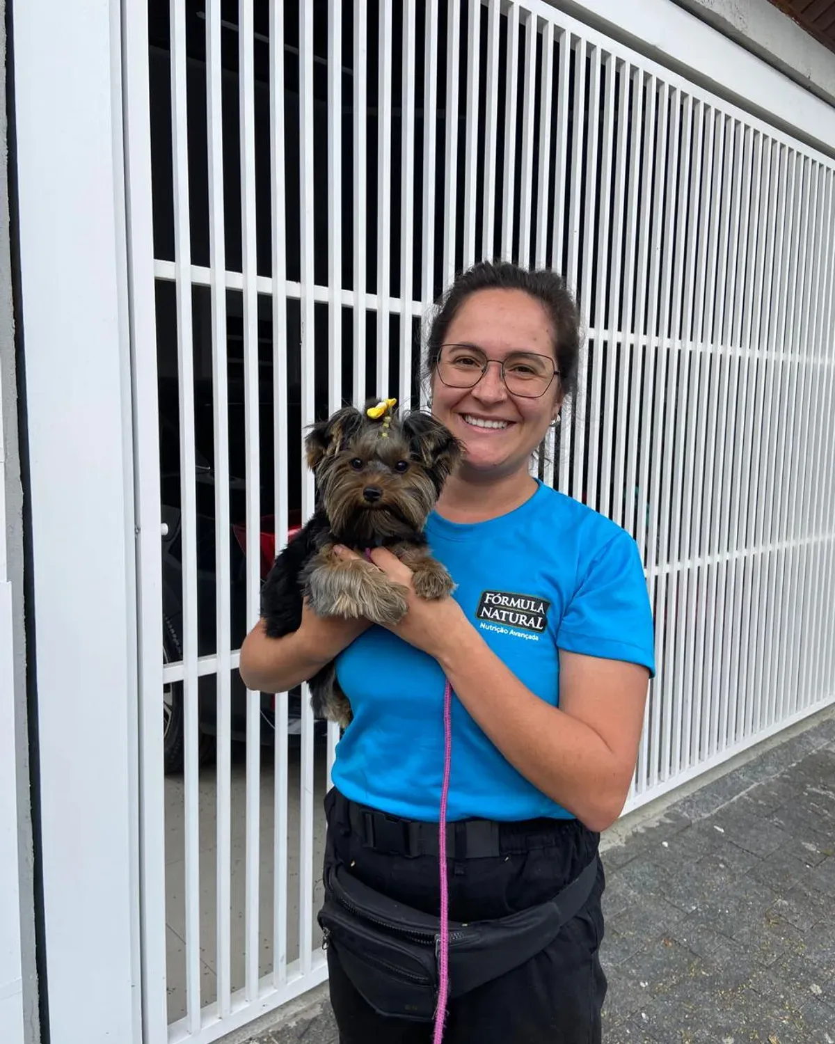 Júlia com um cão durante um atendimento, usando uniforme Fórmula Natural