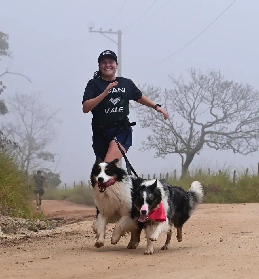 Júlia Martins correndo com dois cães em uma estrada de terra