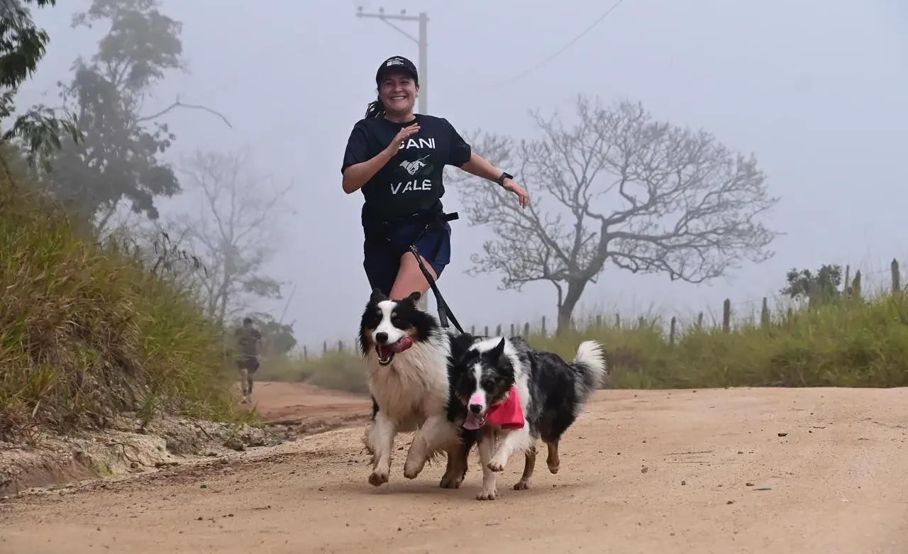 Júlia Martins correndo com dois cães em uma estrada de terra